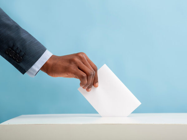 Hand placing ballot into a ballot box