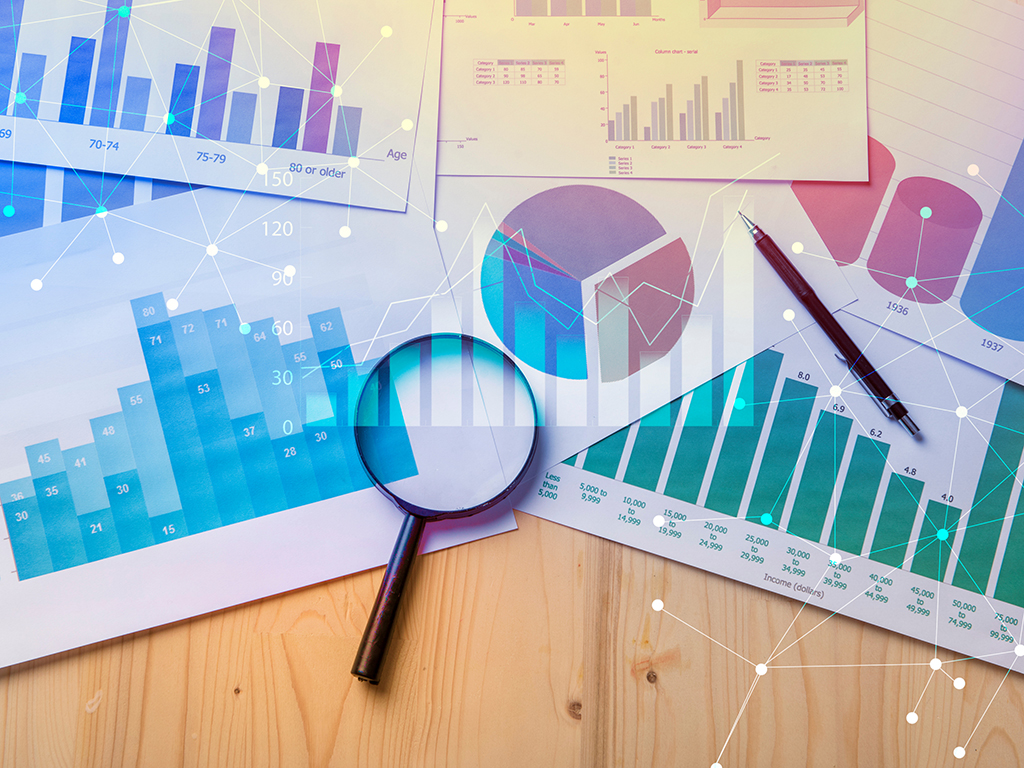 Magnifying glass and documents with analytics data resting on tabletop